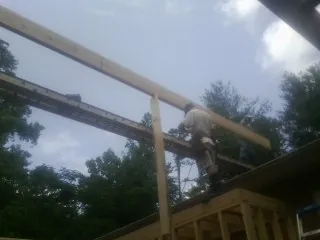 Carpenter setting a ridge beam over a new addition frame — Ice Dam Removal by Roofing Brothers in Erath
