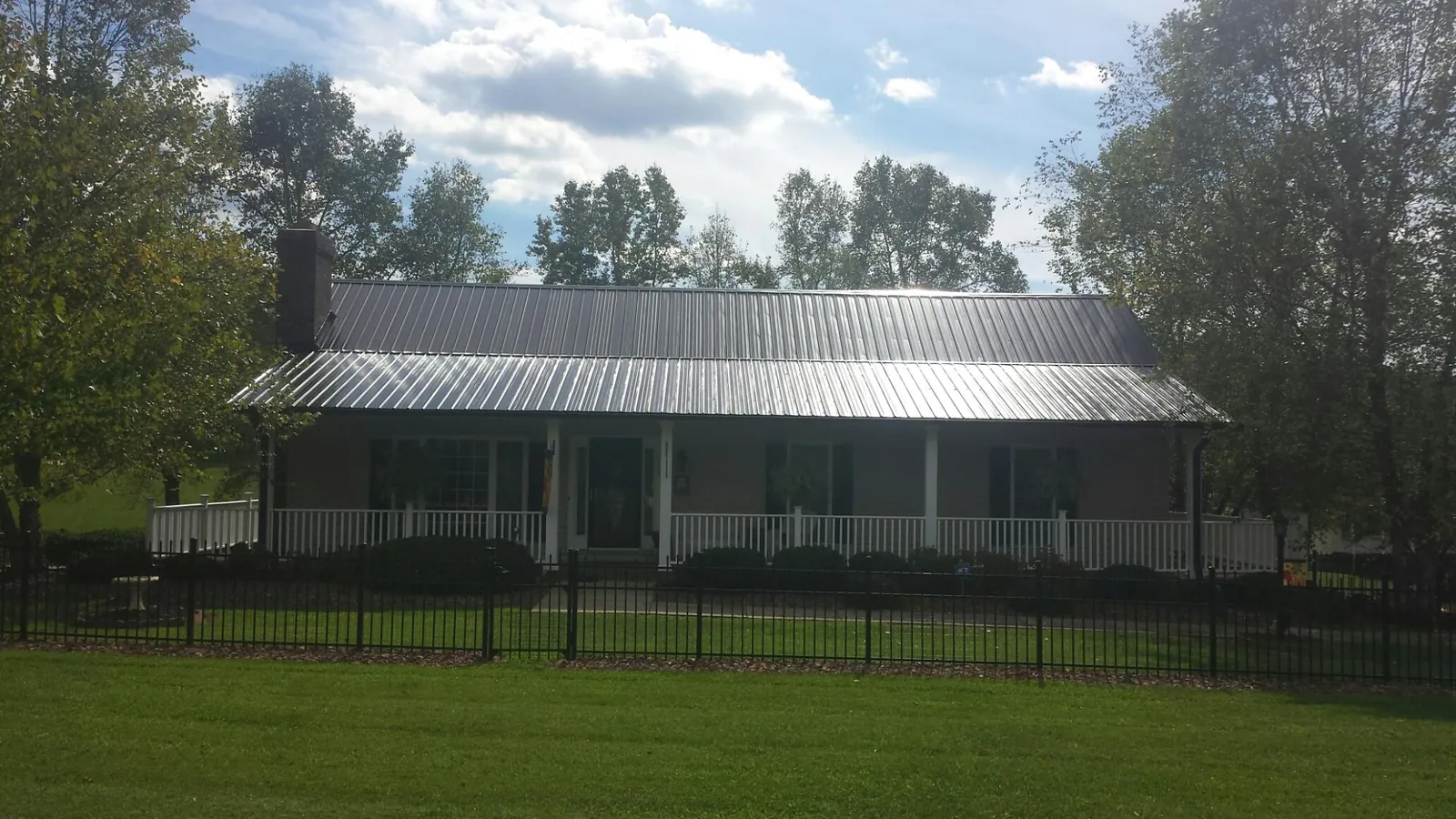 Gray metal roof on a brick ranch with a full width front porch — Gutter Guard Installation work by our crew in Erath